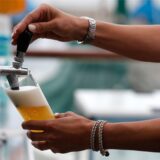 Frau zapft Bier aus Zapfhahn.