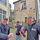 Drei Männer stehen auf einer Hauswand. Zwei halten eine Spraydose in der Hand. Im Hintergrund ist das mit Graffitibild an der Hauswand zu sehen.