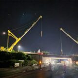 Eine A1-Autobahnbrücke bei Nacht. Links und rechts steht jeweils ein Kran. Die Baustelle ist beleuchtet.