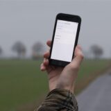 Ein Mann lässt auf einem Feldweg sein Smartphone nach Netzbetreibern suchen.