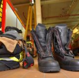 Stiefel stehen in der Feuerwache. Links sind Feuerwehrfahrzeuge zu sehen.