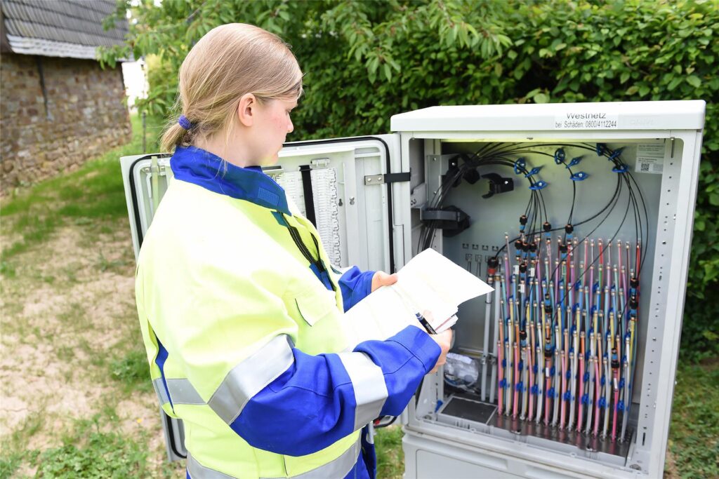 Technikerin vor Glasfaserkabeln