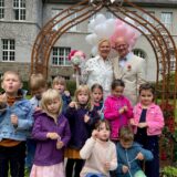 Ein Brautpaar steht vor dem Rathaus in Schwerte. Kita-Kinder mit Seifenblasen stehen davor.
