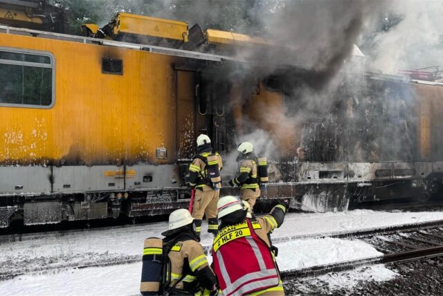 Einsatzkräfte der Feuerwehr löschen einen brennenden Bauzug. Ein Bauwagen ist auf der Bahnstrecke zwischen Gruiten und Hochdahl (Kreis Mettmann) in Brand geraten. Niemand sei verletzt worden, teilte die Feuerwehr am Donnerstagabend mit.