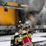 Einsatzkräfte der Feuerwehr löschen einen brennenden Bauzug. Ein Bauwagen ist auf der Bahnstrecke zwischen Gruiten und Hochdahl (Kreis Mettmann) in Brand geraten. Niemand sei verletzt worden, teilte die Feuerwehr am Donnerstagabend mit.