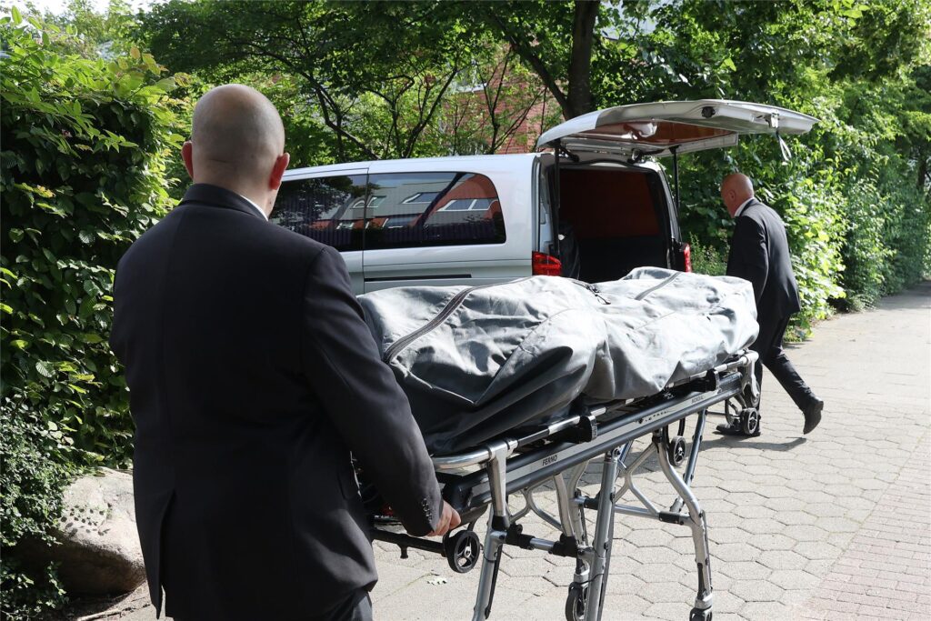 Der Leichnam einer getöteten Person wird am Vormittag in Hamburg-Rahlstedt von einem Bestattungsunternehmen abtransportiert. Bei einem Einsatz des Spezialeinsatzkommandos (SEK) in Hamburg ist ein Mann tödlich verletzt worden.

