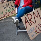 Demonstrierende von Long-Covid-Selbsthilfegruppen aus Rheinland-Pfalz protestieren mit Schildern „Ich will mein Leben zurück“ und „Arm durch Covid“ vor einem Auftritt von Bundeskanzler Scholz.