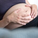 Schwangere Frau hält sich den Bauch.