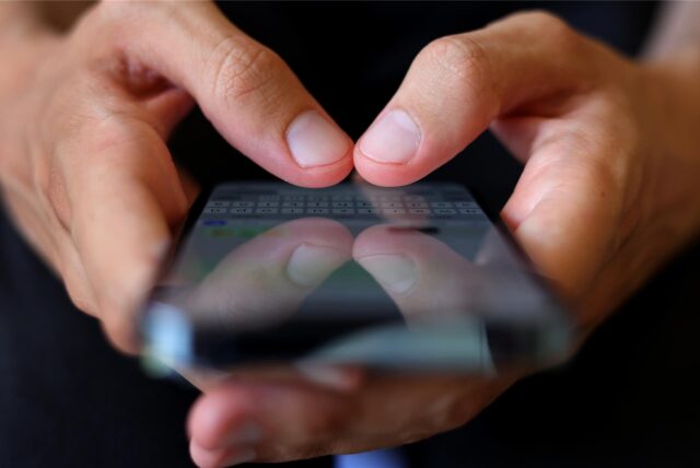 Ein Jugendlicher tippt auf einem Smartphone eine WhatsApp Nachricht.