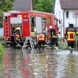 Einsatzkräfte der Feuerwehr im Einsatz nach einem Unwetter mit Starkregen auf einer überfluteten Straße.