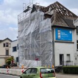 Autos fahren an einem eingerüsteten Haus in Unna vorbei. Das Gebäude am Ostring soll abgerissen werden.