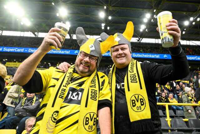 Zwei Fans prosten vor einem BVB-Spiel dem Fotografen zu.
