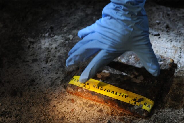 in Mitarbeiter des Strahlenschutzes der Asse GmbH hebt am 22.06.2011 im Atommülllager Asse bei Remlingen (Landkreis Wolfenbüttel) bekleidet mit einem blauen Schutzhandschuh, einen mit einer Warnung vor Radioaktivität beklebten Metalldeckel an