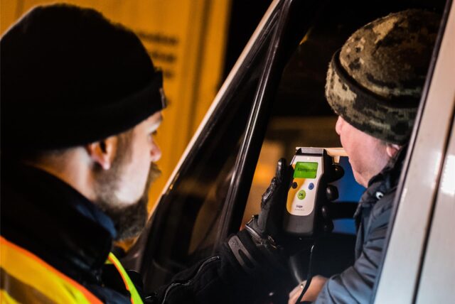 Ein Polizist kontrolliert einen Autofahrer auf Alkoholgenuss.