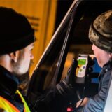 Ein Polizist kontrolliert einen Autofahrer auf Alkoholgenuss.
