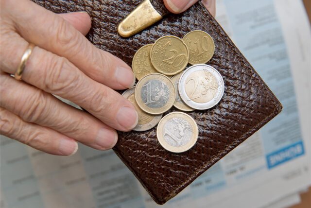 Eine ältere Frau zählt Euromünzen auf einem Portemonnaie