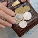 Eine ältere Frau zählt Euromünzen auf einem Portemonnaie
