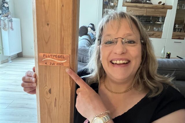 Katja Westhoff an dem Balken mit der Flutpegel-Plakette.