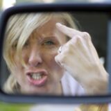 Eine Frau zeigt als Autofahrerin den Vogel.