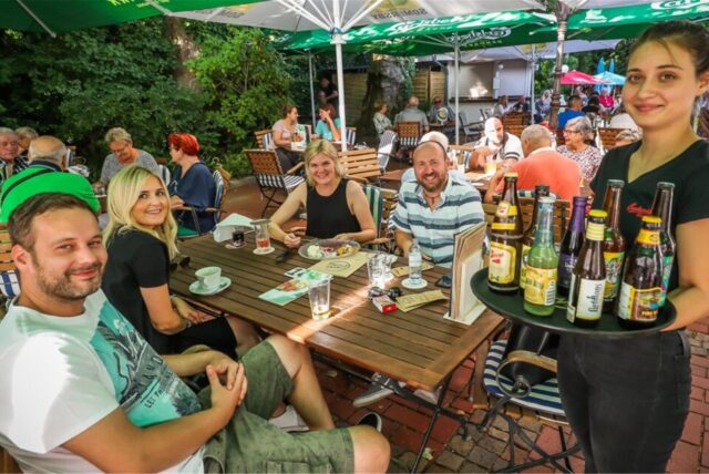 Eine Mitarbeiterin von „Hopfen & Salz“ in Dortmund-Lütgendortmund serviert Besuchern des Biergartens Getränke.