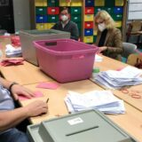 Menschen an einem Tisch mit Briefwahlunterlagen
