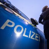 Ein Polizist steht an seinem Streifenwagen.