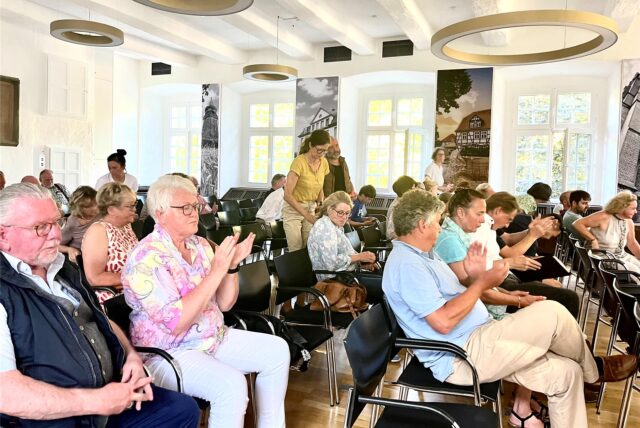 Bürgermeisterin Sabina Müller steht mit einem Mikrofon vor einer Draufsicht des Geländes.