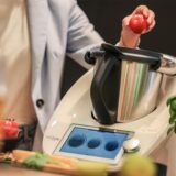 Ein Hand gibt eine Tomate in einen Thermomix.