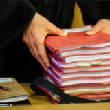 Ein Staatsanwalt legt einen Stapel Akten vor Prozessbeginn auf seinen Tisch im Gericht.