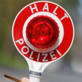 Ein Polizist zieht ein Fahrzeug mit seiner Kelle aus dem Verkehr.