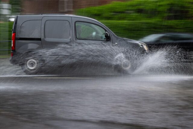 Ein Auto fährt durch eine Wasserlache