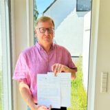 Ralph Froß hält die Rechnungen und Schreiben der DEW in die Kamera.