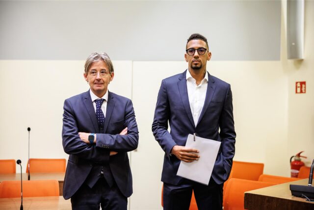 Jérôme Boateng (rechts) hält Unterlagen in der Hand und steht im Gerichtssaal neben seinem Rechtsanwalt Leonard Walischewski (links)