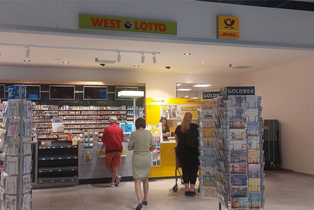 Mehrere Menschen stehen an einem DHL-Paketshop und einem Kiosk in der „Neuen Mühle“.