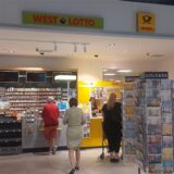 Mehrere Menschen stehen an einem DHL-Paketshop und einem Kiosk in der „Neuen Mühle“.
