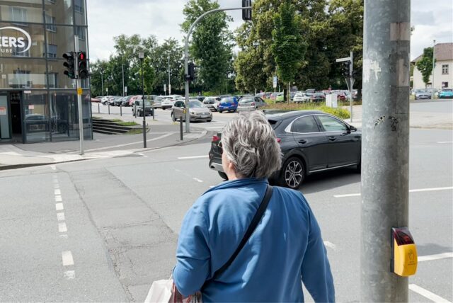 Eine Frau wartet an einer Ampel auf Grün.