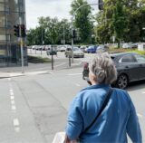 Eine Frau wartet an einer Ampel auf Grün.