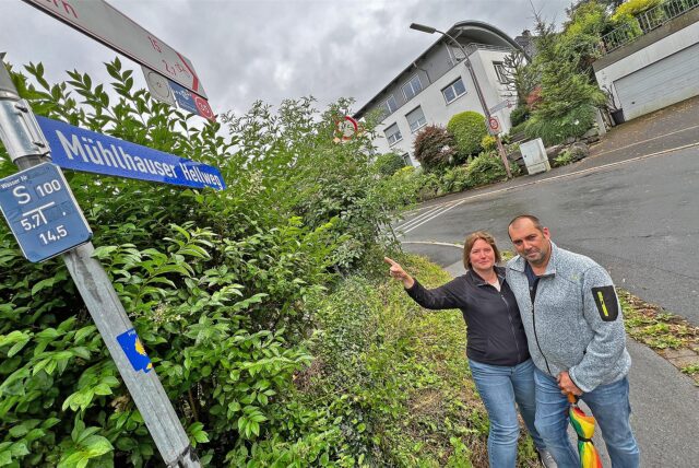 Michaela und Kai Setzer stehen in Unna-Mühlhausen an einem Straßenschild. Die Aufschrift „Mühlhauser Hellweg“ ist falsch.