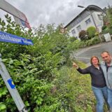 Michaela und Kai Setzer stehen in Unna-Mühlhausen an einem Straßenschild. Die Aufschrift „Mühlhauser Hellweg“ ist falsch.