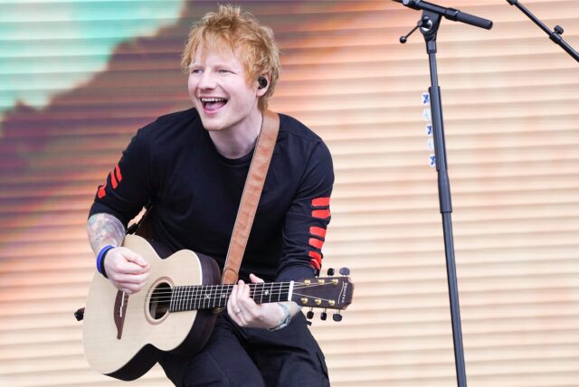 Popkünstler Ed Sheeran spielt Gitarre auf einer Bühne.