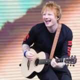 Popkünstler Ed Sheeran spielt Gitarre auf einer Bühne.