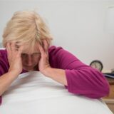 Frau fasst sich an den Kopf.