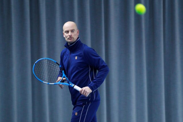 Tennisspieler Andreas Thiveßen mit Schläger und Ball in der Tennishalle.