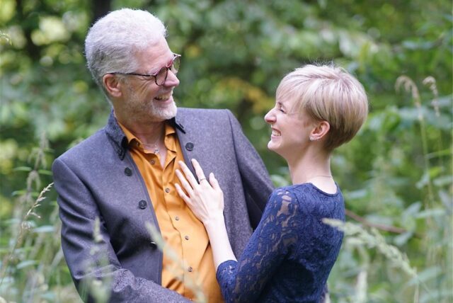Tom Damm (Stadtkirchenpfarrer von Schwerte) und Jana Ecker haben geheiratet. Auf dem Foto stehen sie im Babywald in Wandhofen und lächeln einander an.