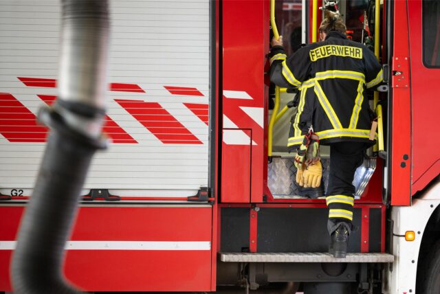 Eine Feuerwehrfrau steigt in den Einsatzwagen.