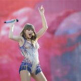 Die US-amerikanische Singer-Songwriterin Taylor Swift steht auf der Bühne und streckt ihre Arme in die Luft