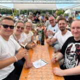 Besucher der Veranstaltung „Weingenuss am Hafen“ in Bergkamen prosten sich mit Weingläsern zu