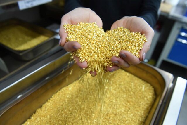 Goldgranulat, das einen Feingoldgehalt von 99,99 Prozent hat, rieselt bei der Firma Allgemeine Gold- und Silberscheideanstalt AG Agosi in Pforzheim (Baden-Württemberg) durch zwei Hände.