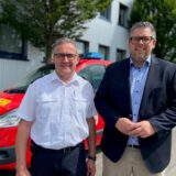 Feuerwehrchef Wilhelm Müller und Dezernent Niklas Luhmann stehen vor einem Feuerwehrfahrzeug in Schwerte.