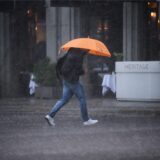 Ein Mann geht am frühen Mittag bei Starkregen über eine Straße in Berlin-Mitte.